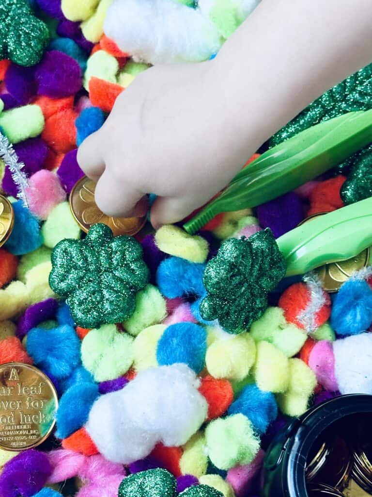 kid playing inside St patrick's day sensory bin