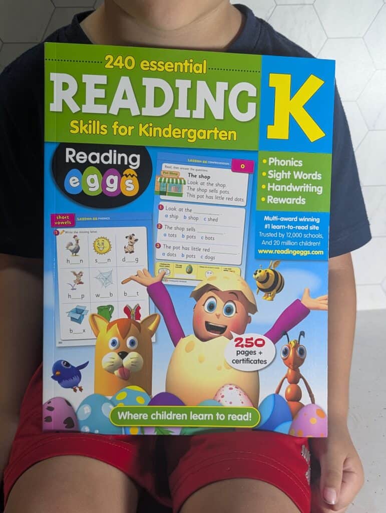 child holding up the reading eggs book