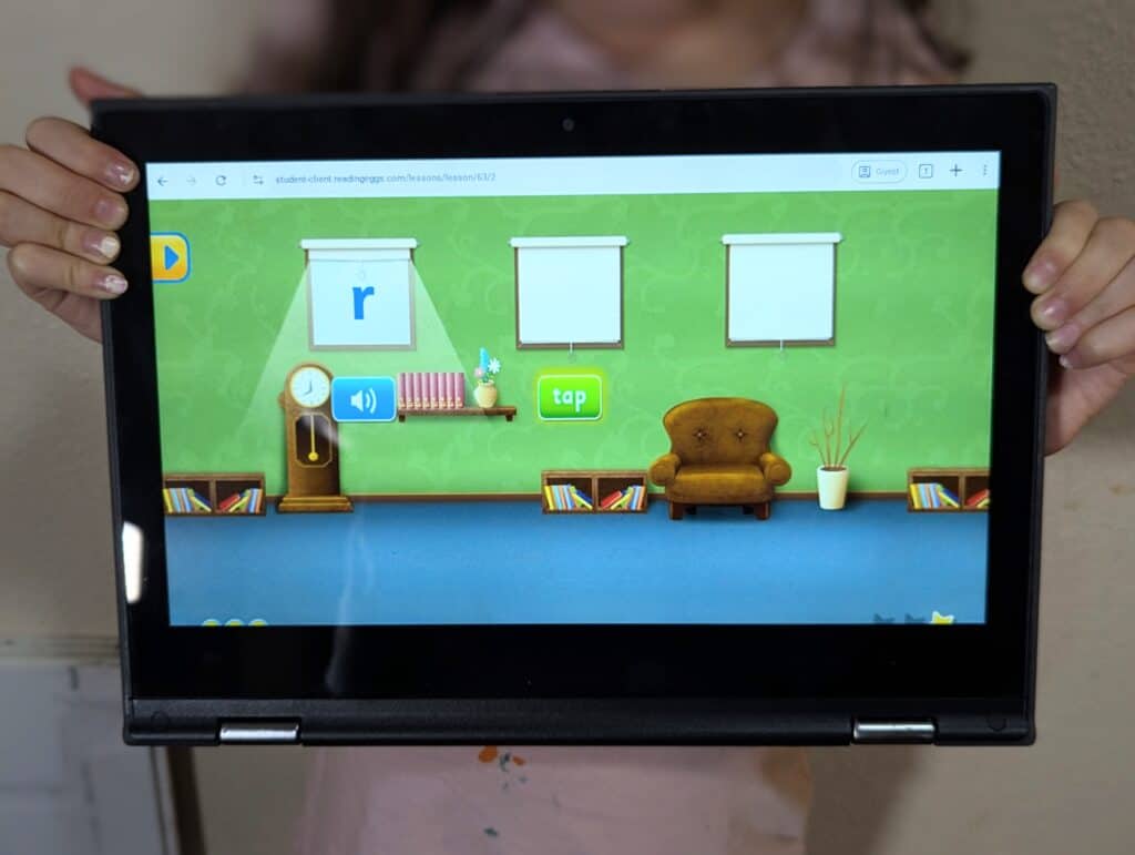 child holding up tablet with reading eggs on it 